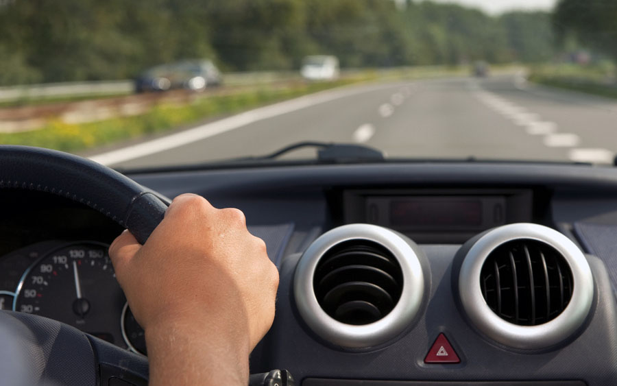 Driving a car with a hand on the steering wheel